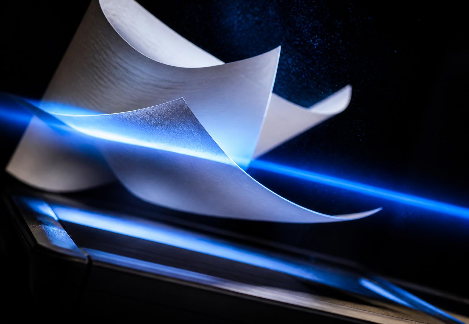 Sheets of paper caught in a beam of blue scanner light